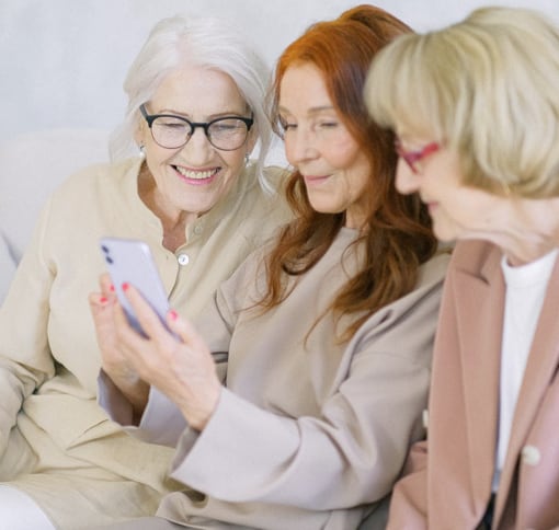 Three elderly woman engaged in a video chat through a mobile phone
